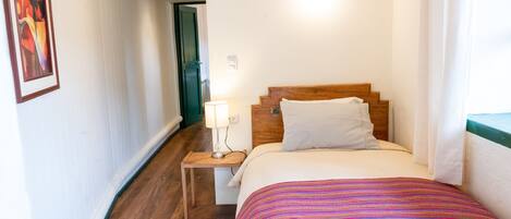 A hotel room with a wooden bed, a nightstand with a lamp, and a framed picture on the wall.