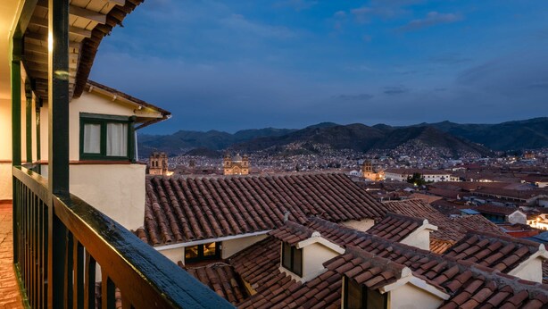 A cityscape with terracotta rooftops and a prominent church in the distance. - Hostal Corihuasi (Cusco)
