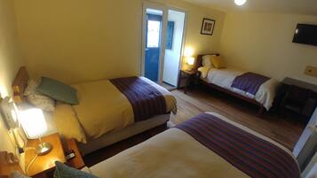 A hotel room with two beds, a desk, a chair, a TV, and a sliding door to the outside.