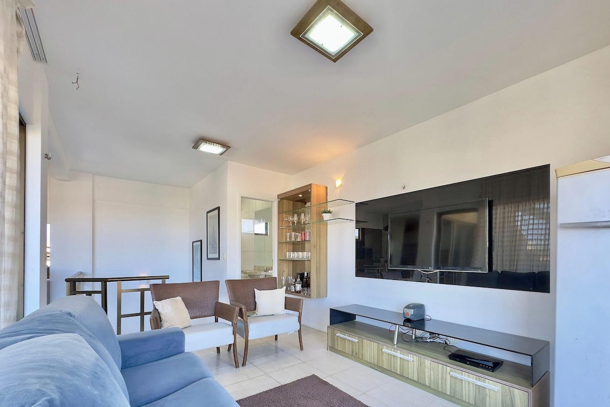 A modern living room with a sofa, TV, and a glass cabinet.
