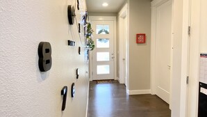 A hallway with a wooden floor, white walls, and a door at the end.