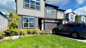 A two-story residential building with a garage, a well-maintained lawn, and a parked car.
