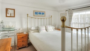 A bedroom with a bed, bedside table, dresser, and a window with curtains. - Waltham House (Lyme Regis)