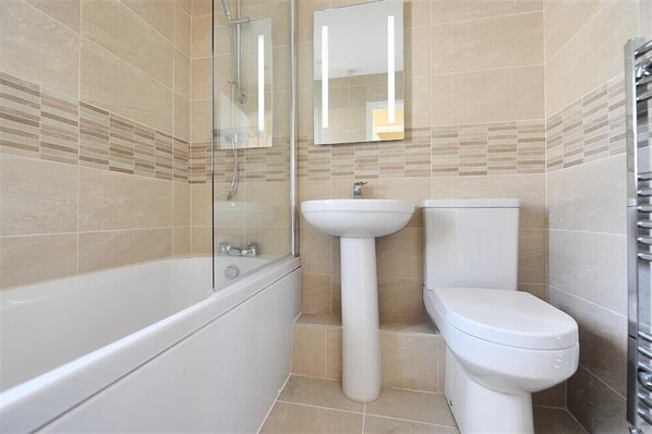 A bathroom with a bathtub, a sink, and a toilet. - The Old Bakehouse (Lyme Regis)