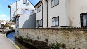 A narrow canal with a brick wall on one side and a white building with multiple windows on the other. - The Old Bakehouse (Lyme Regis)