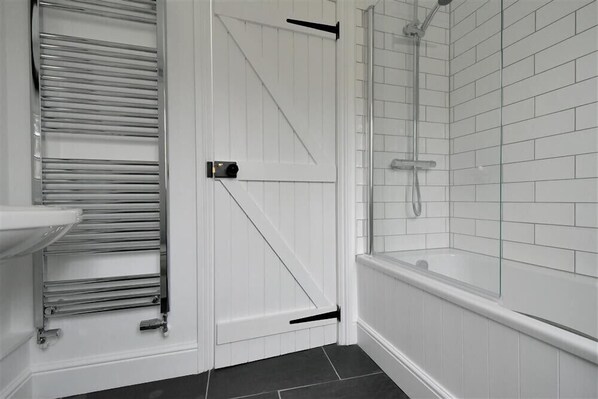 A bathroom with a white door, a glass shower enclosure, and a white sink.