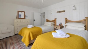 A hotel room with two beds, a wooden dresser, a mirror, and a striped carpet. - 12 Mill Green (Lyme Regis)