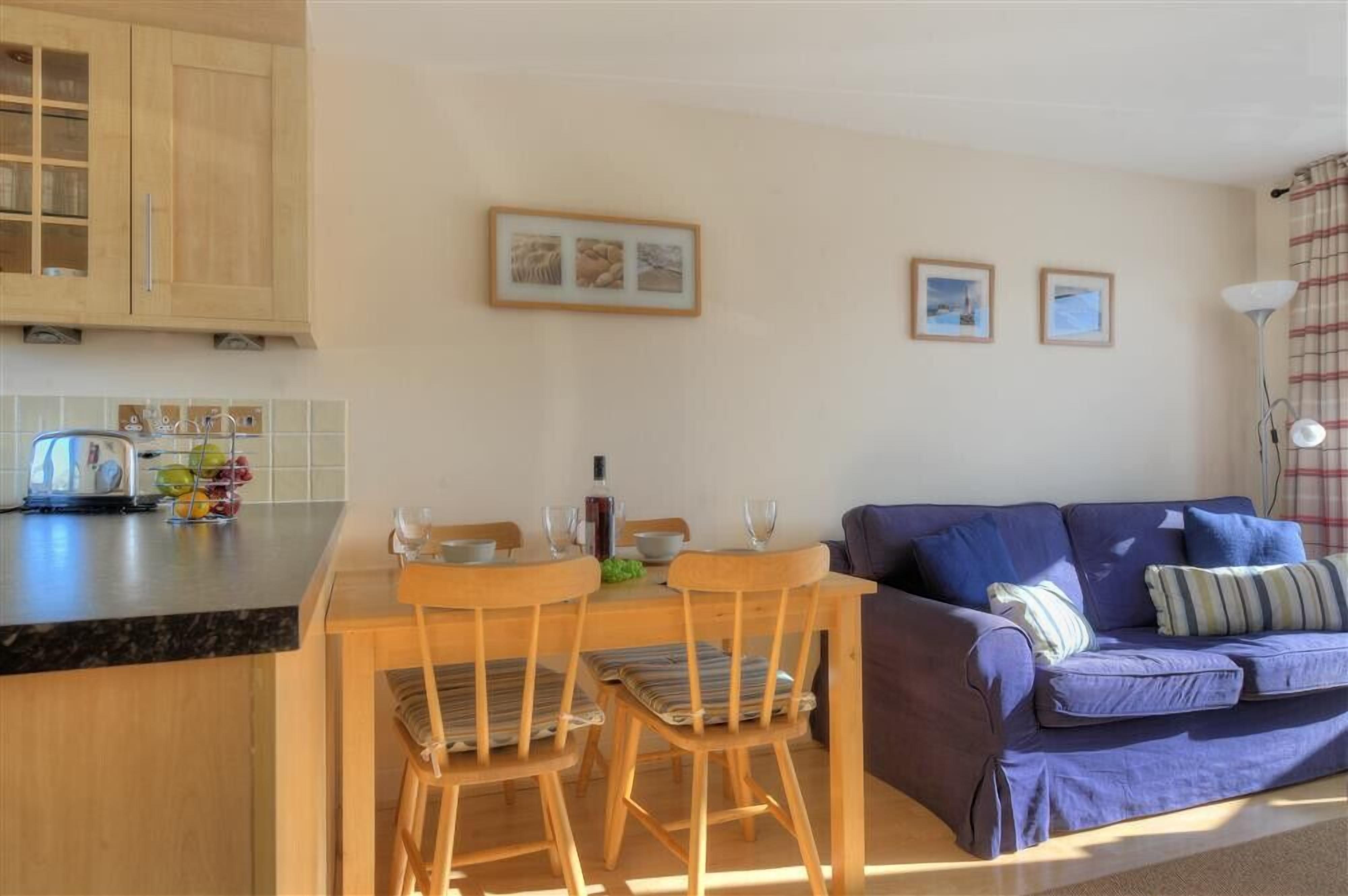 A compact living space with a kitchen area, dining table, and a sofa.