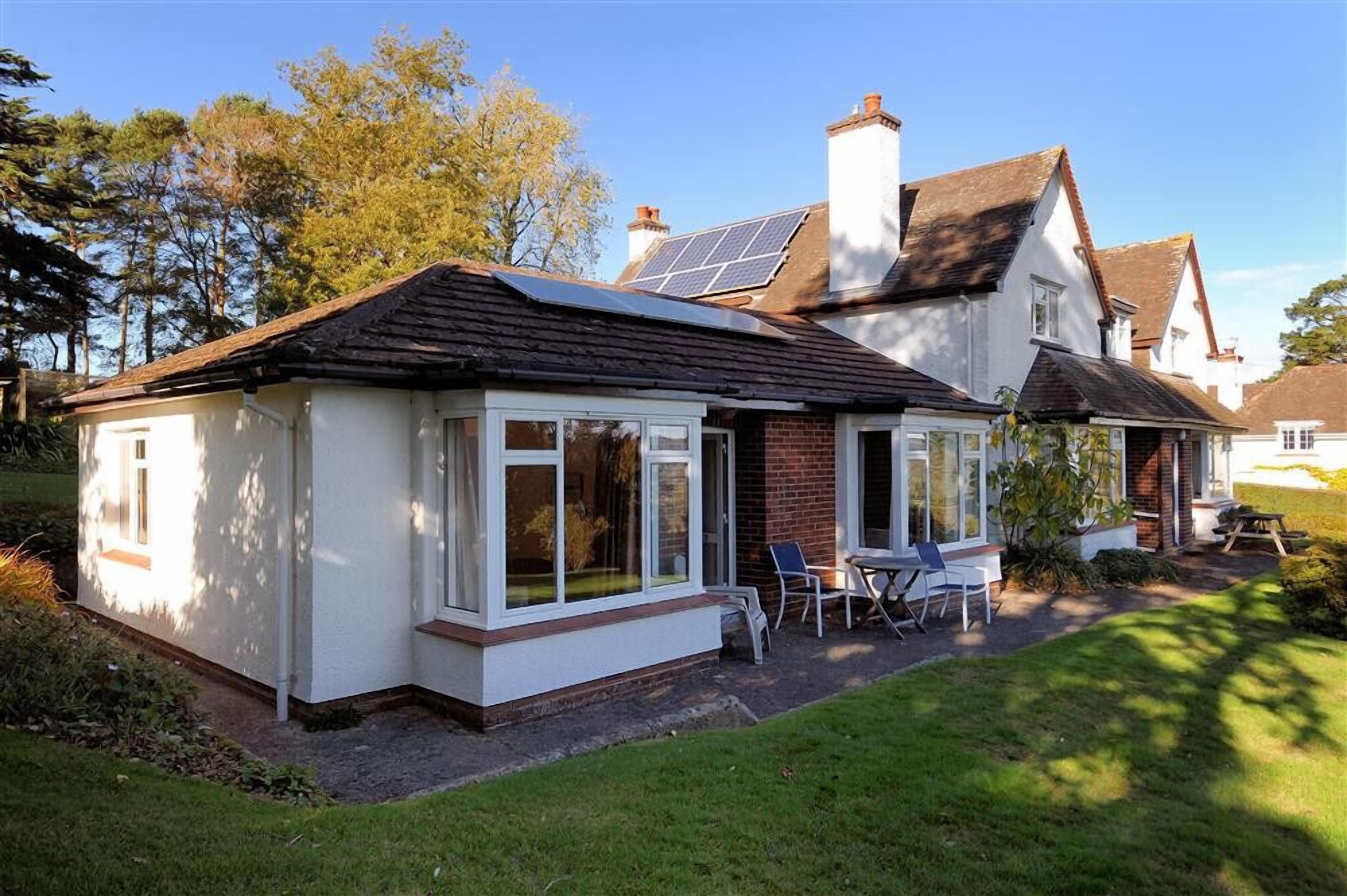 A house with a covered patio, solar panels, and a garden.