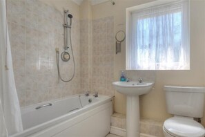 A bathroom with a bathtub, sink, and toilet. - 4 Riverside Cottages (Bridport)