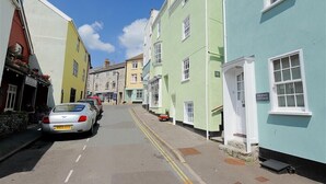 Une rue étroite bordée de bâtiments aux couleurs vives, dont une petite maison portant l’inscription « Phoenix Cottage ».