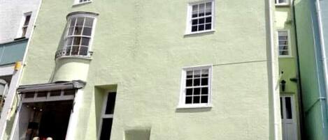 A light green building with multiple windows and a corner entrance.