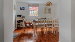 Un coin repas avec des meubles blancs, une fenêtre donnant sur un beau paysage et un four à micro-ondes posé sur une étagère.