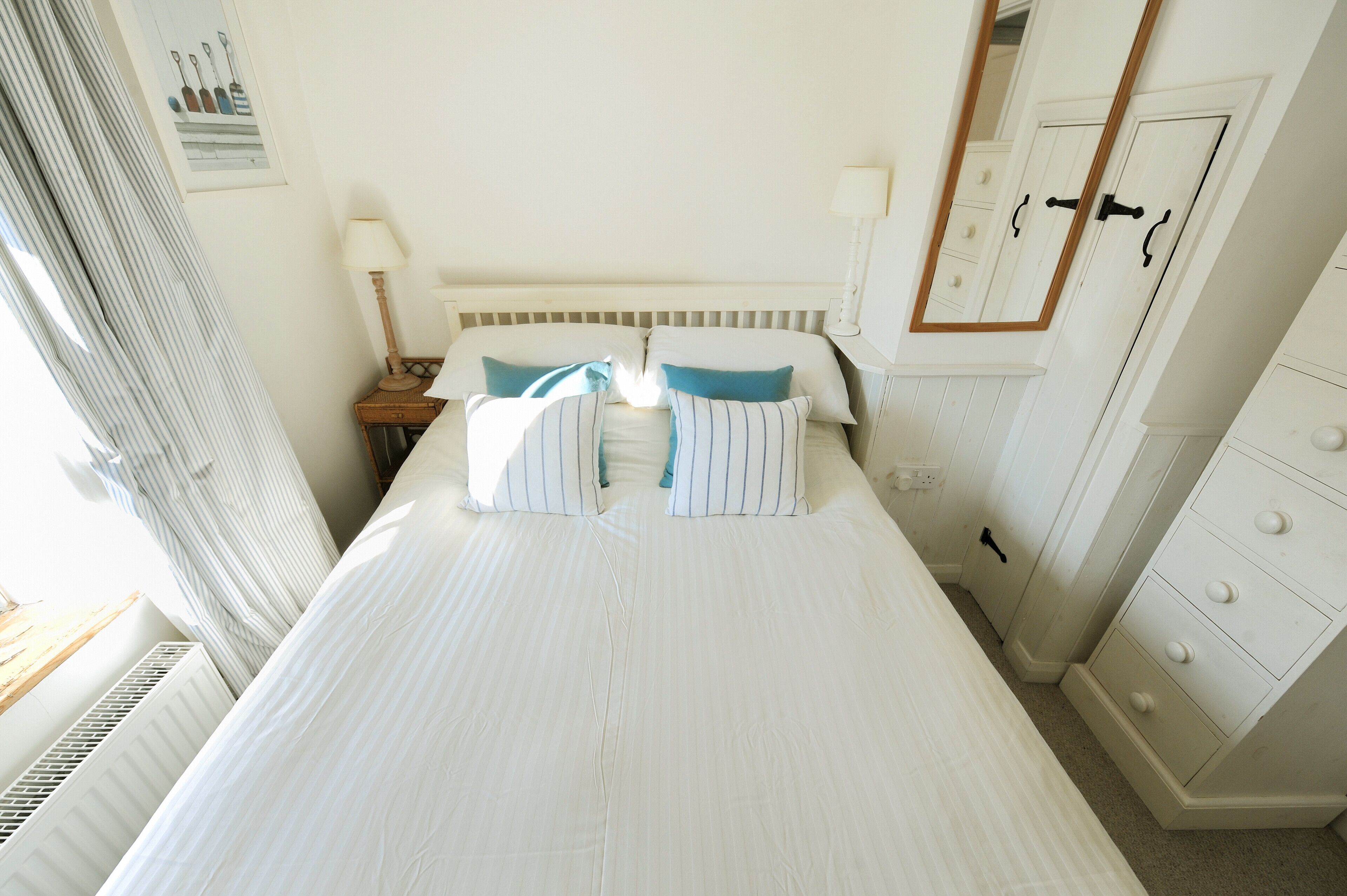A neatly made bed with striped pillows, a bedside lamp, and a nightstand.