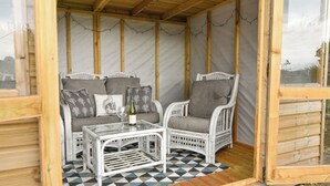 A cozy outdoor seating area with wicker furniture, a glass table, and a patterned floor. - Byeways (Axminster)
