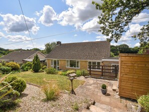 A residential property with a tiled roof, a fenced garden, and a small patio area. - Byeways (Axminster)