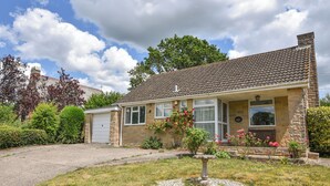 A two-story house with a stone facade, a tiled roof, and a front garden with a birdbath. - Byeways (Axminster)