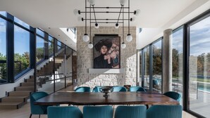 A modern dining area with a large wooden table, teal chairs, and a stone accent wall. - Villa New Vintage with Pool (Pazin)