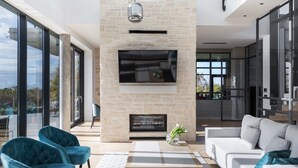 A modern living room with a stone fireplace, a flat-screen TV, and a large window offering a view of the outdoors. - Villa New Vintage with Pool (Pazin)