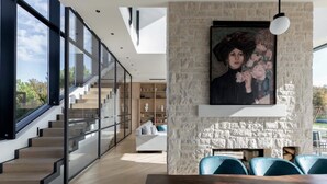 A modern interior with a staircase, a dining area, and a stone wall with a painting. - Villa New Vintage with Pool (Pazin)