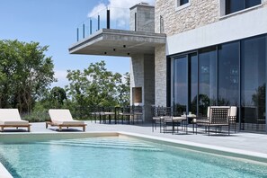 A modern outdoor pool area with lounge chairs and a dining setup.
