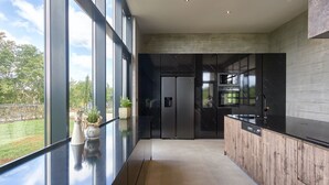 A modern kitchen with a black countertop, stainless steel appliances, and a large window overlooking a garden. - Villa New Vintage with Pool (Pazin)