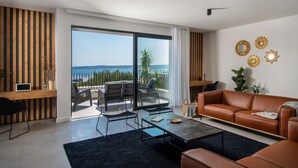A modern living room with a leather sofa, a coffee table, and a balcony with a view of the sea. - Villa Maremonte with Pool (Kaštel Kambelovac)