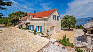 A stone house with a red-tiled roof, blue shutters, and a stone staircase leading to the entrance. - Luxury Villa Aerius with Pool (Pučišća)