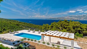 A pool area with lounge chairs and a pergola overlooking a coastal landscape. - Luxury Villa Aerius with Pool (Pučišća)