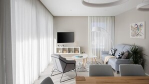 A modern living room with a grey sofa, a coffee table, and a TV mounted on the wall.