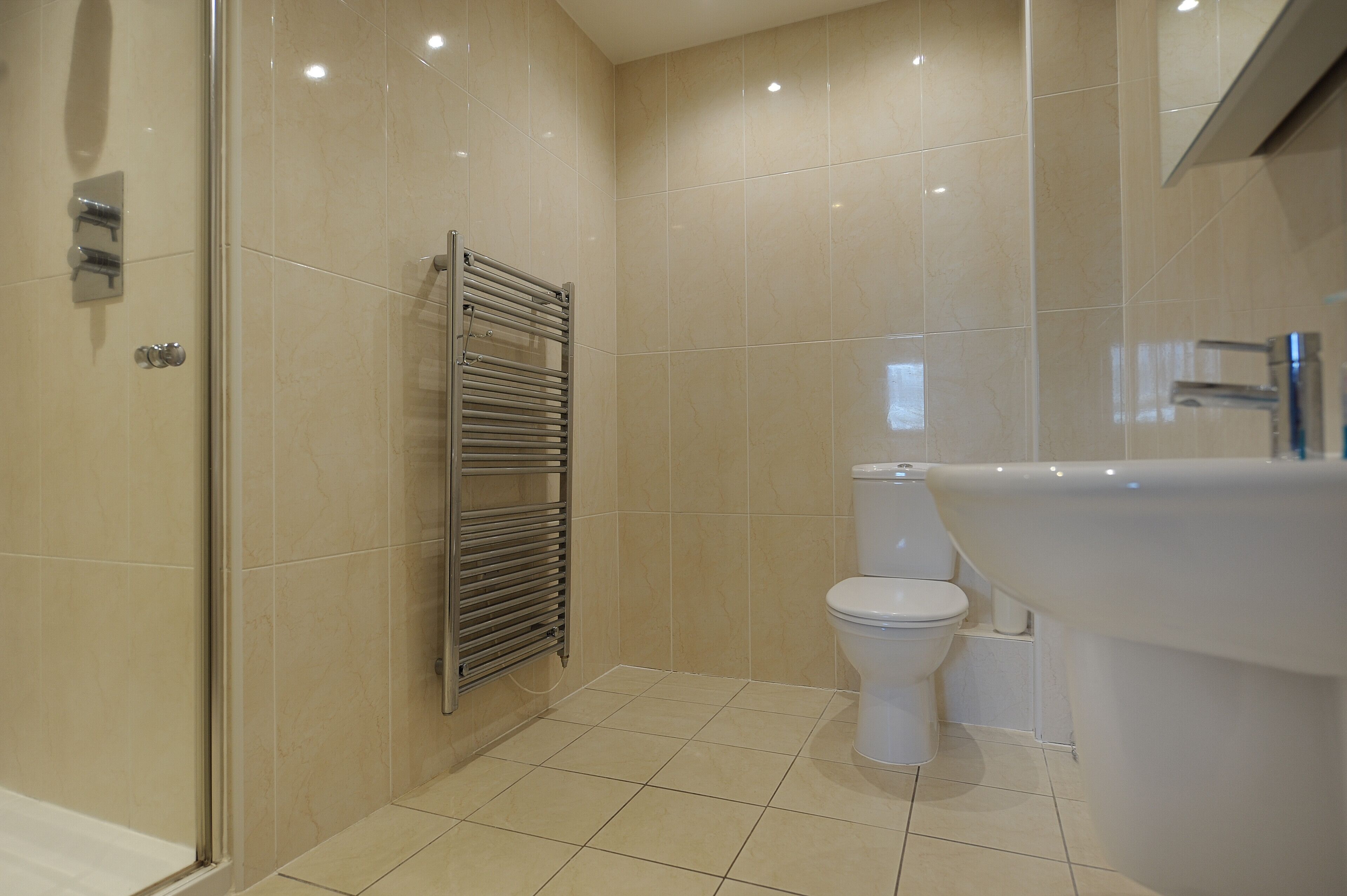 A modern bathroom with a glass shower enclosure, a built-in toilet, and a freestanding bathtub.