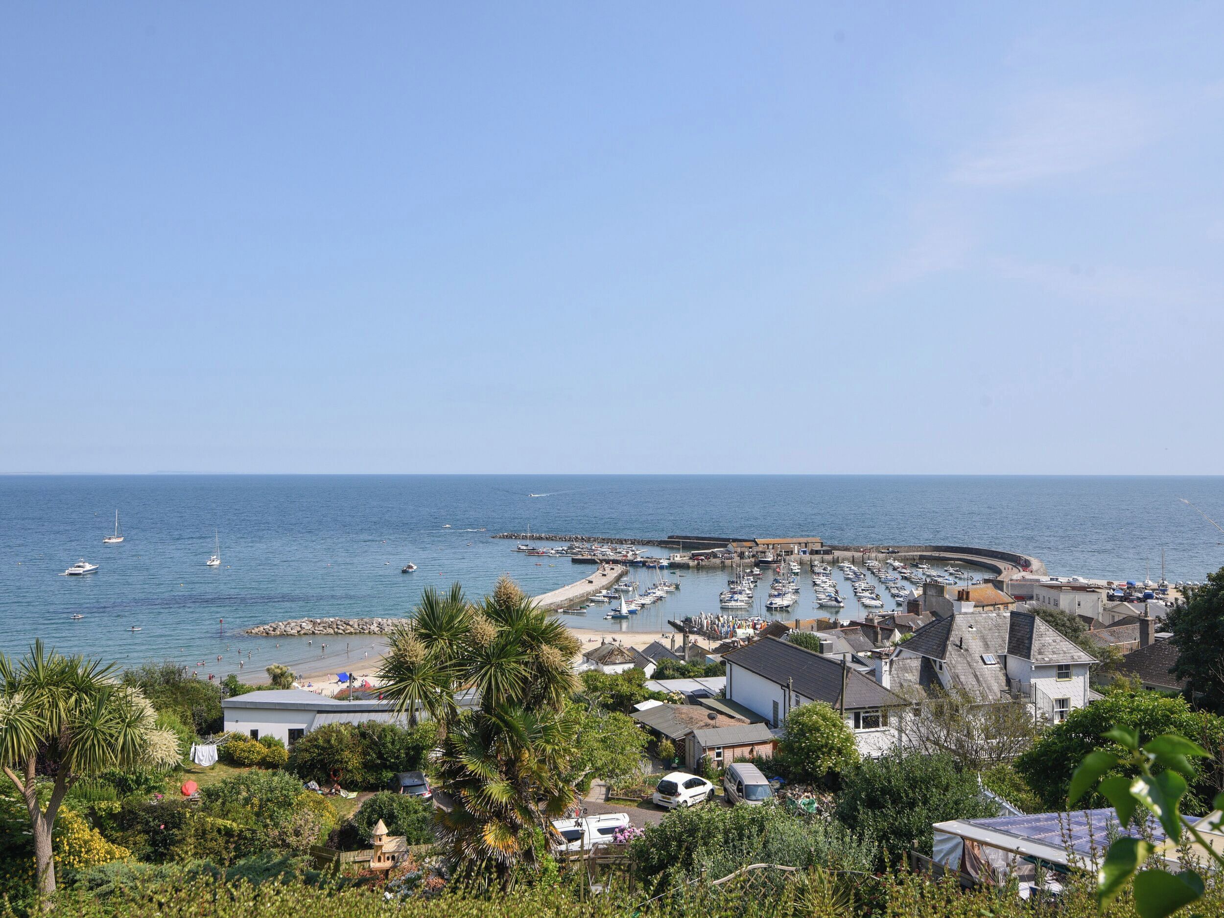 A coastal town with a marina, houses, and a clear view of the sea.