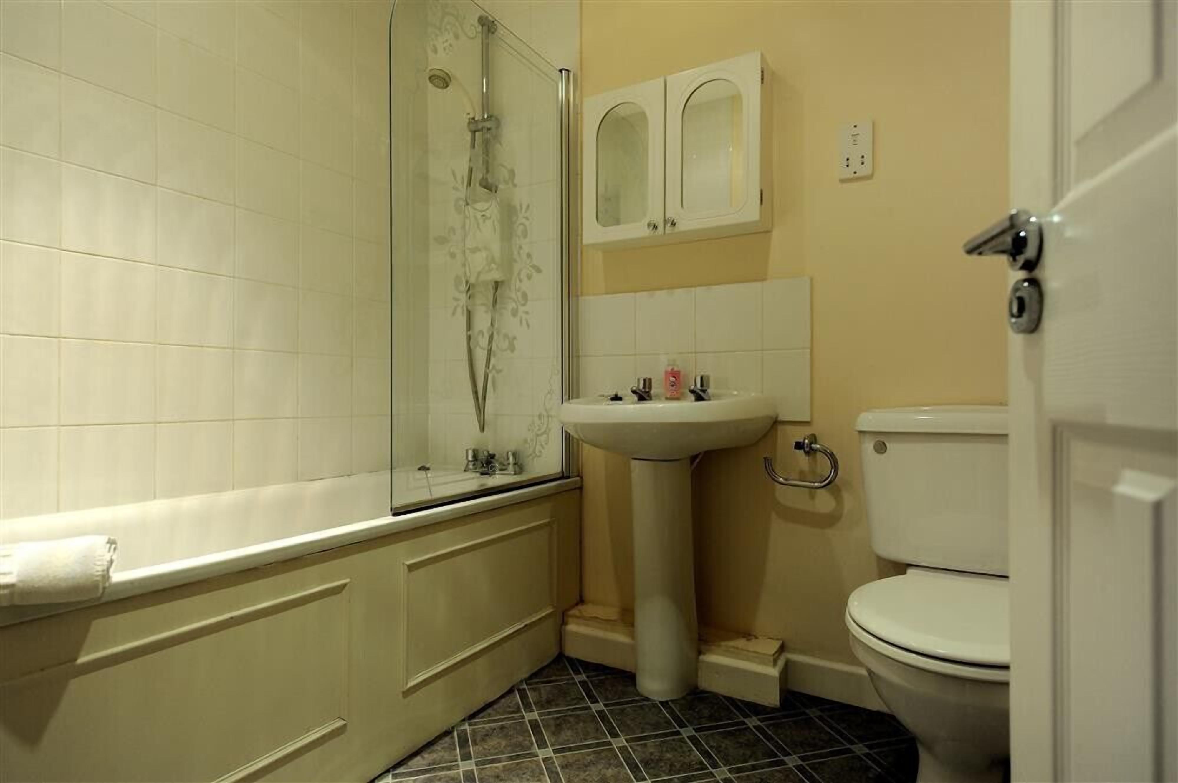 Ein Badezimmer mit Dusche, Waschbecken, Toilette und einem Schrank über dem Waschbecken.