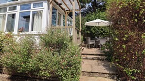 A conservatory with a wooden frame and glass panels, connected to a house by a wooden deck. - Little Ascot (Lyme Regis)