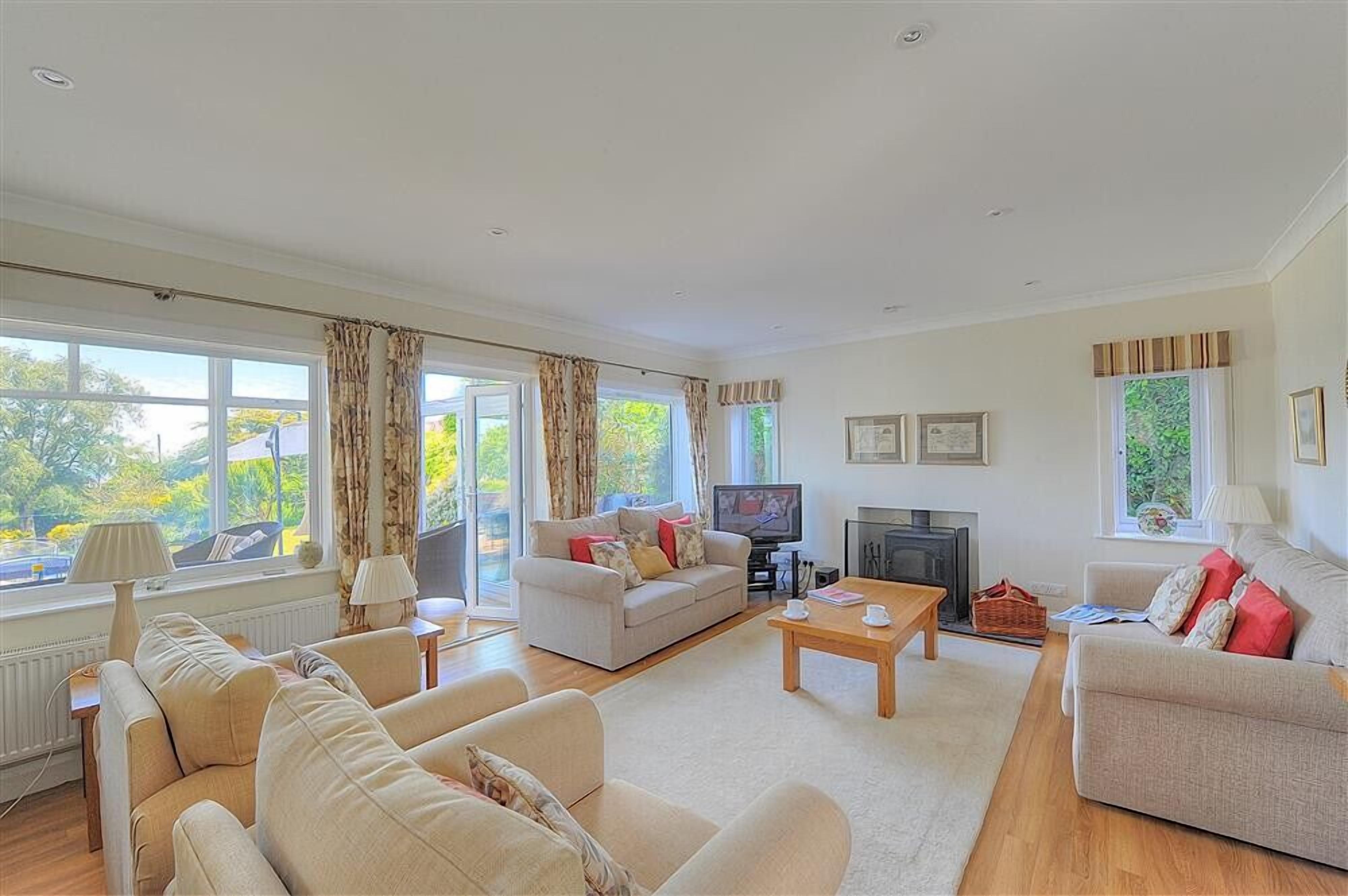 A spacious living room with a sofa set, a television, and a fireplace.