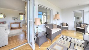 Un salon spacieux comprenant un canapé, des fauteuils, une table basse et une grande fenêtre.