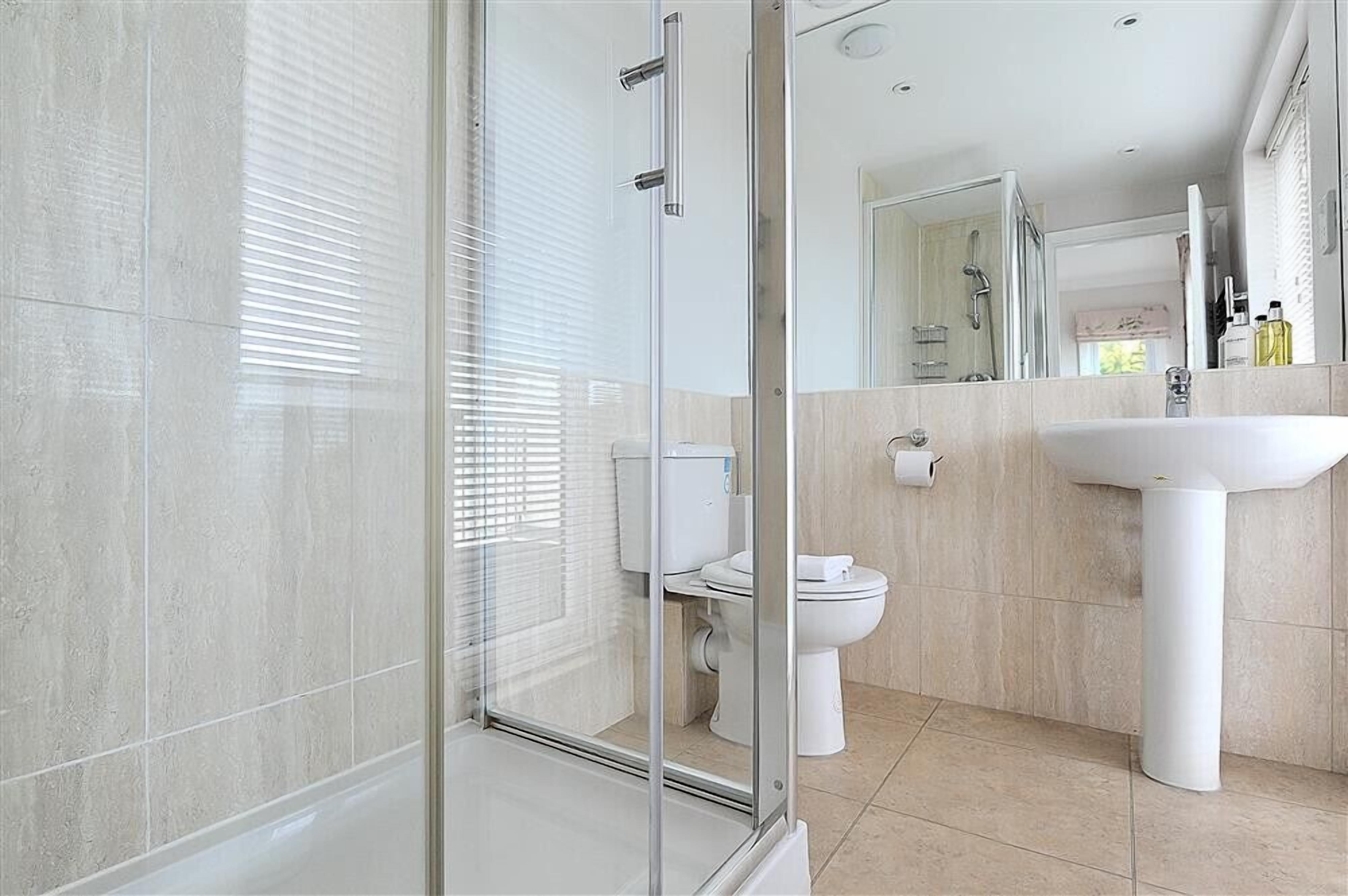 A modern bathroom with a glass shower enclosure, a toilet, and a sink.