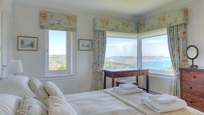 Une chambre avec un lit, un bureau et une vue sur la mer.