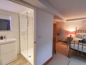 Une chambre à coucher comprenant un lit, une table de chevet, une lampe et une porte en bois donnant sur une autre pièce.