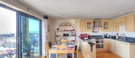 Eine moderne Küche mit Holzschränken, einem eingebauten Backofen und einem großen Fenster mit Blick auf einen Balkon.