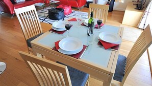A dining area with a glass table set for four, surrounded by wooden chairs. - Sandstones (Bridport)