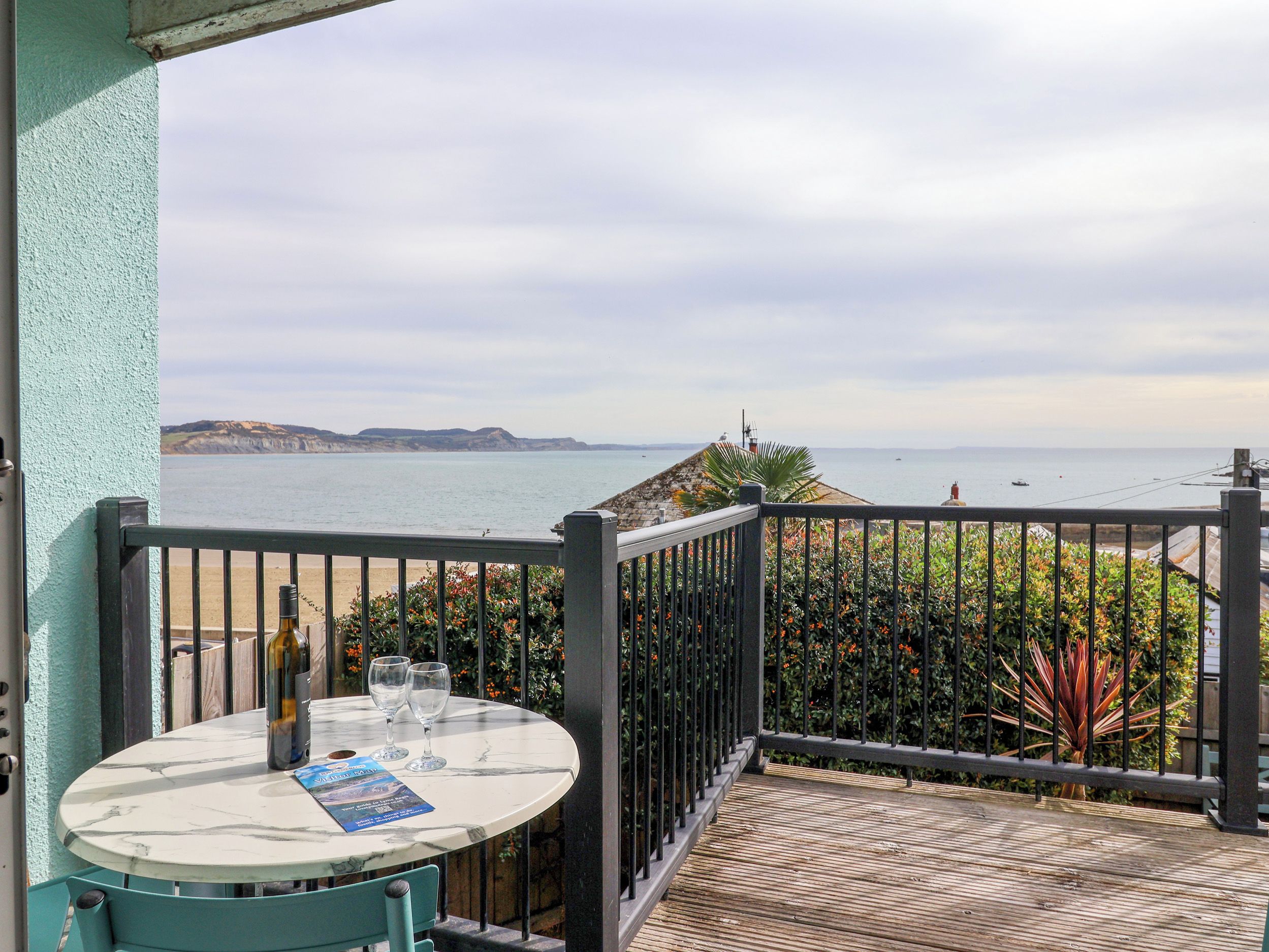 Una terraza con mesa y sillas, con vistas a la costa, acantilados y el mar.