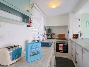 A kitchen with a toaster, a kettle, a microwave, and a wooden cutting board. - 1 Wellhayes (Lyme Regis)