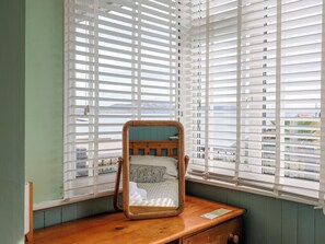 A room with a wooden dresser, a mirror, and a window with white blinds. - 1 Wellhayes (Lyme Regis)