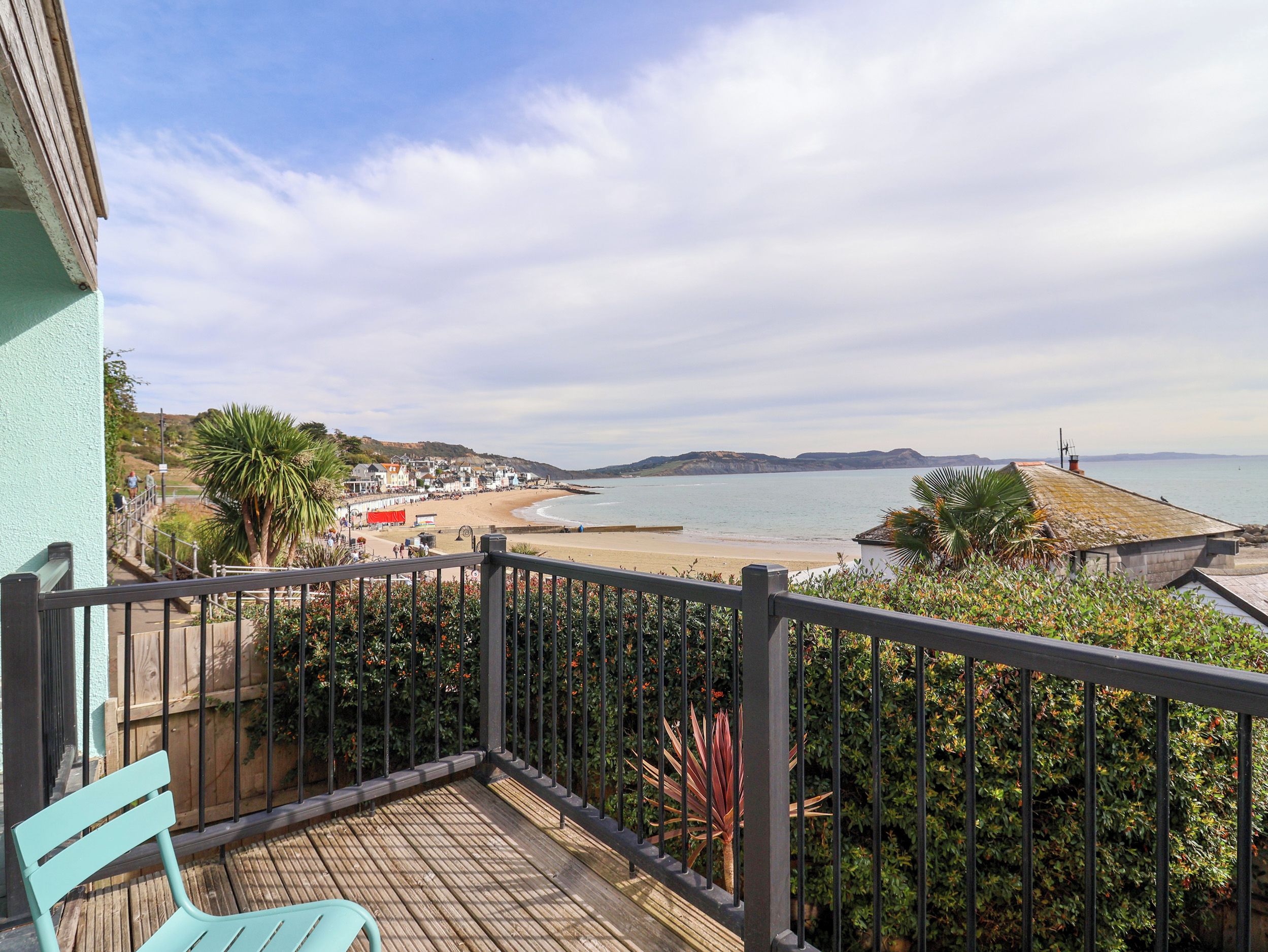 A balcony with a view of a beach and a distant coastline.