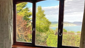 A window with a view of a lake, trees, and distant hills. - High Cliff Orchard (Lyme Regis)