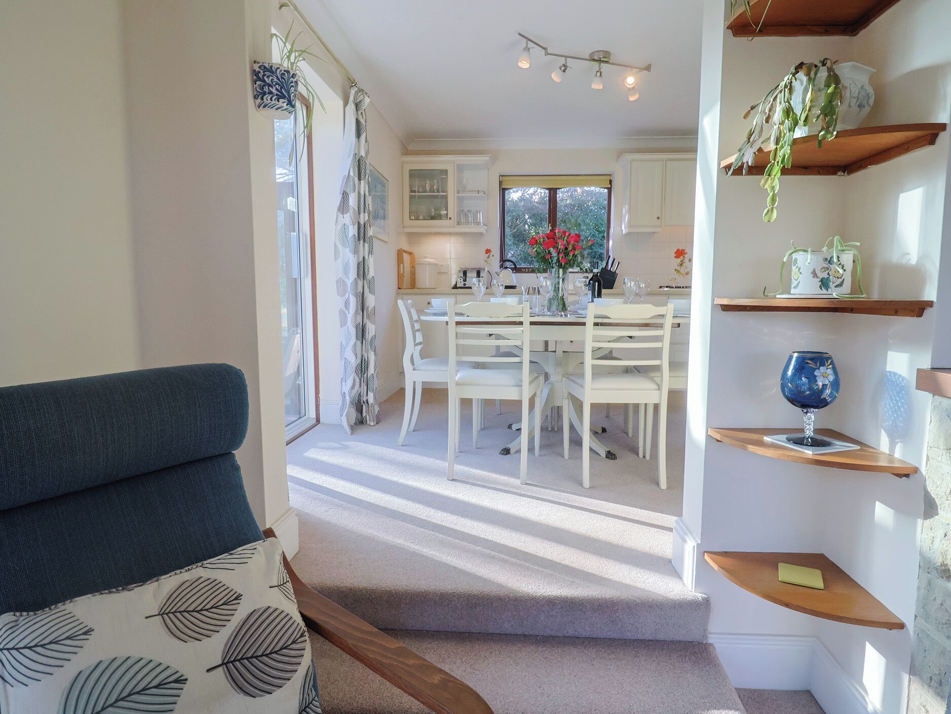 A cozy living room with a sofa and a staircase leading to a dining area with a table and chairs.