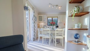 A cozy living room with a sofa and a staircase leading to a dining area with a table and chairs. - High Cliff Orchard (Lyme Regis)