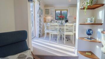 A cozy living room with a sofa and a staircase leading to a dining area with a table and chairs.