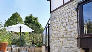 An outdoor patio with a table and chairs, a potted plant, and a white umbrella. - High Cliff Orchard (Lyme Regis)